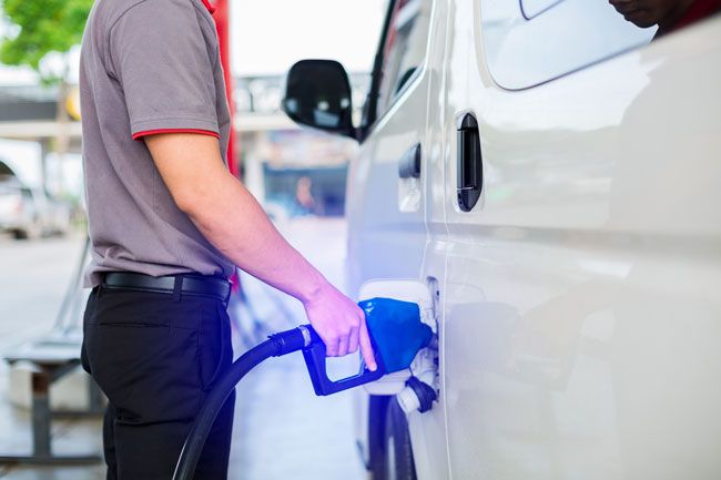 A fleet driver fueling his business’s van at a gas station.