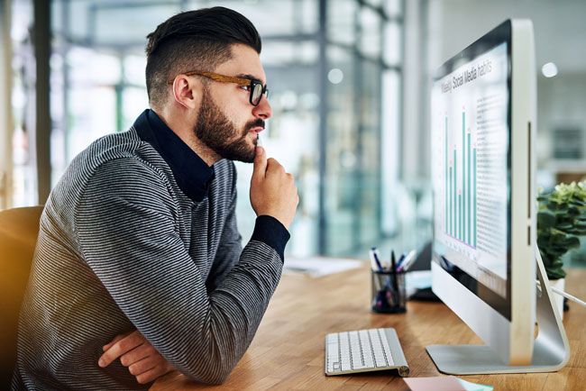 A small business owner sits at a desk reviewing the data and analytics from the fleet cards used by his drivers.