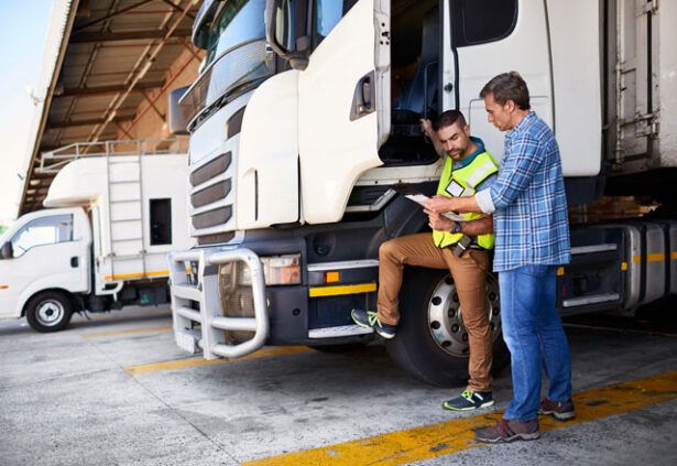 An HVAC fleet driver is getting direction from the HVAC owner about new routes while standing outside the truck.